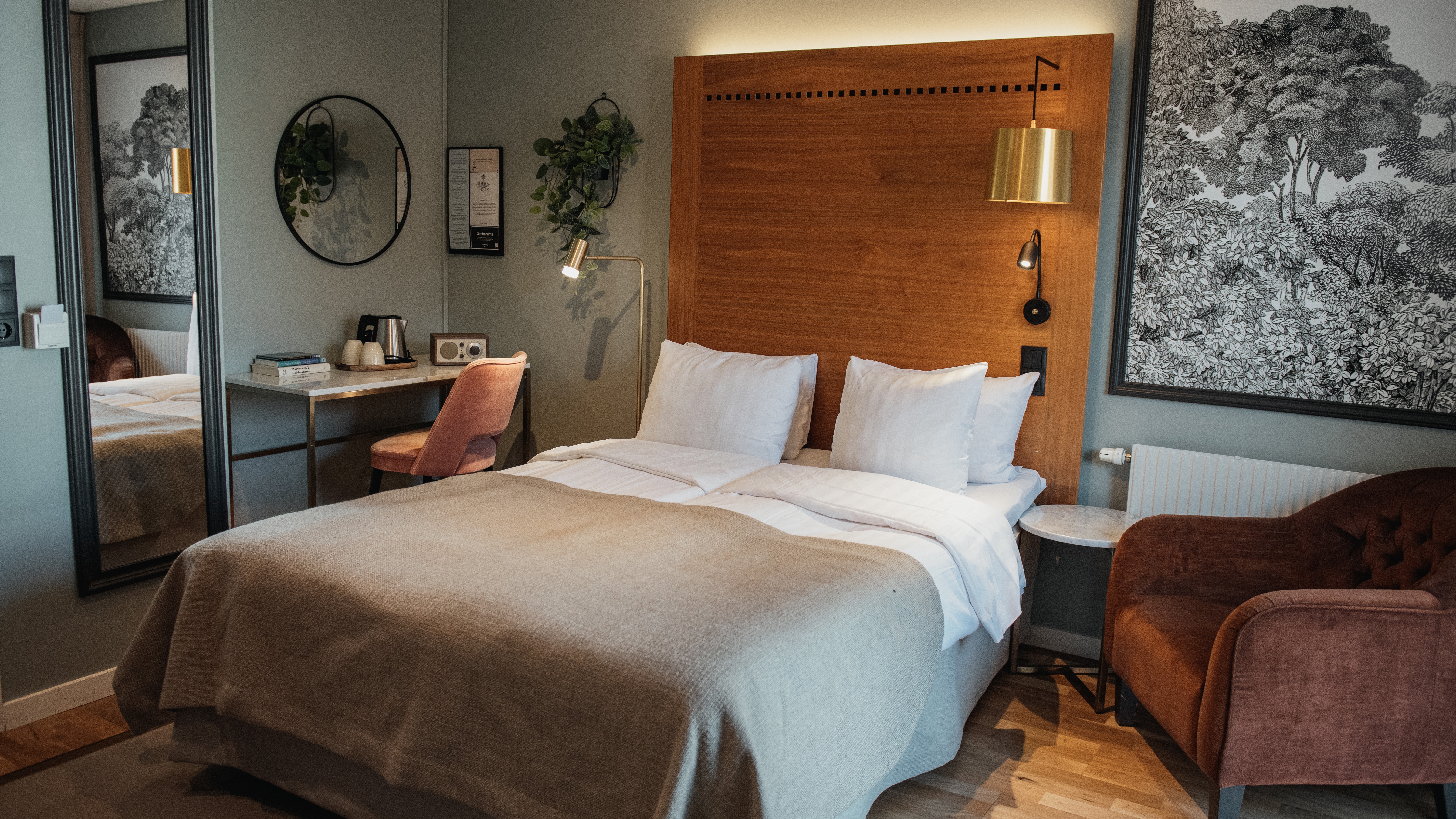 Et velutstyrt hotellrom med en stor seng, et skrivebordsområde med stol og en komfortabel lenestol, designet for avslapning og produktivitet.