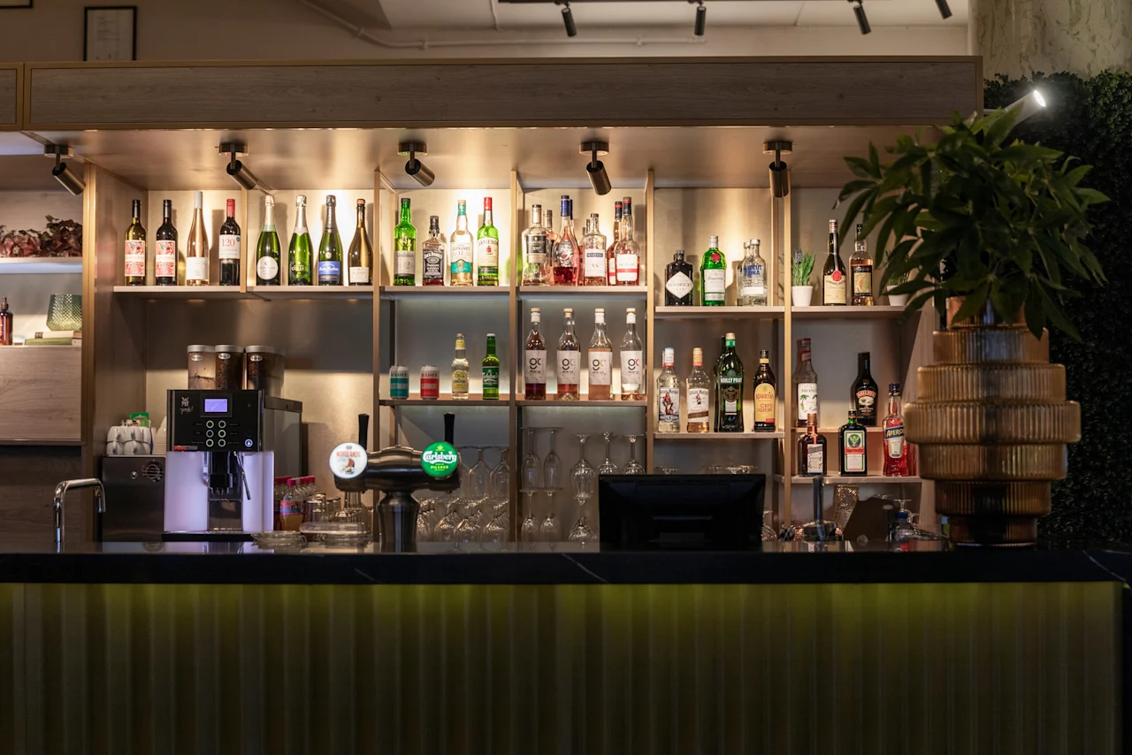 A stylish bar at Home Hotel Grand Bodø, featuring a wide selection of beverages, coffee, and draft beer.