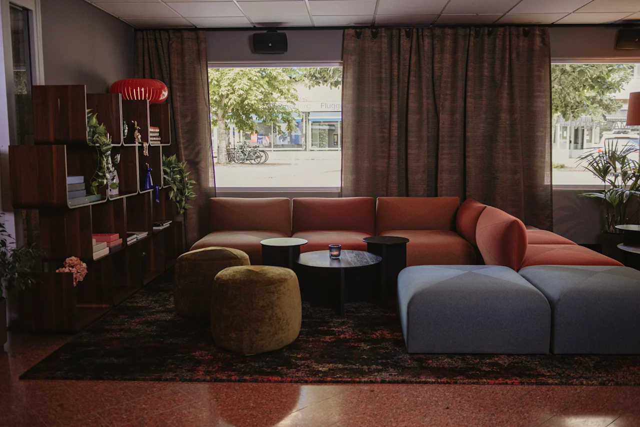 Et koselig salongområde med en stor sofa og puffer, ideelt for avslapning. Utenfor er en gate med et skilt som leser Flug.