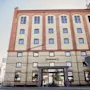 Suuri tiilirakennus, jossa on paljon ikkunoita ja moderni lasisisäänkäynti. Tekstit 'MAGASINET' ja 'HAMNGATAN' näkyvät.