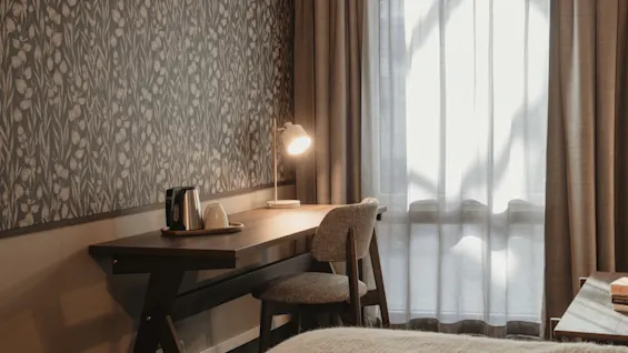 Et koselig hotellrom med skrivebordsområde, klart for arbeid eller avslapning, badet i naturlig lys.