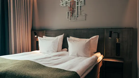 A cozy hotel room with a neatly made bed, soft lighting, and modern decor.