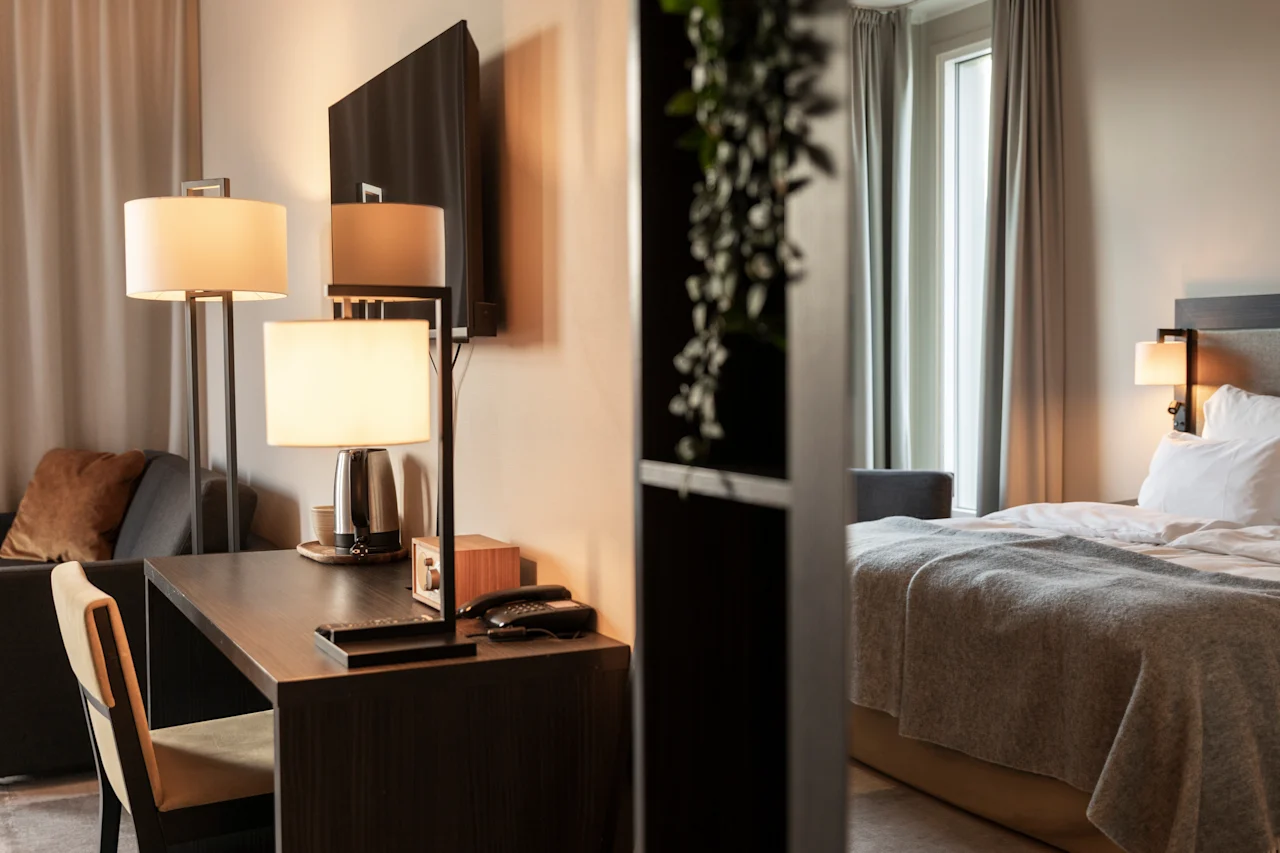 Et hyggeligt hotelværelse med skrivebord og en behagelig seng, perfekt til arbejde og afslapning.