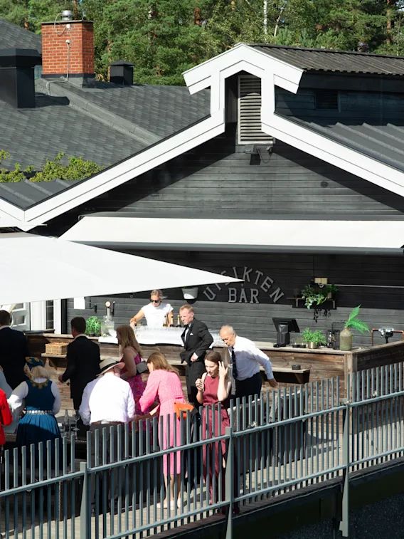Utendørs arrangement på terrassen ved "Utsikten Bar" med gjester i festantrekk og bunader.