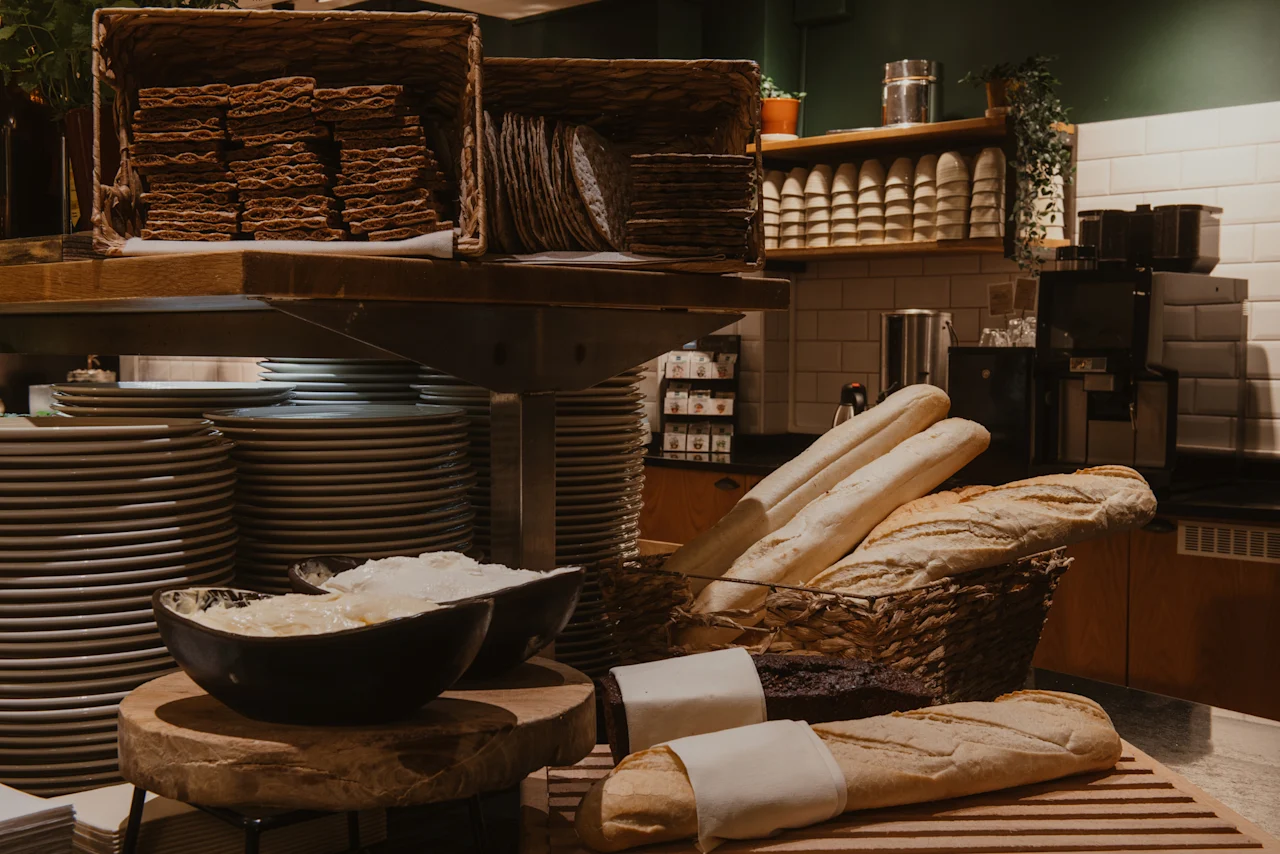 En buffé på Home Hotel Grand, Helsingborg, med färskt bröd, kex och smör, med staplar av tallrikar redo för gäster.