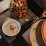 A warm bowl of soup with croutons and fresh herbs, ready to be served from a large pot, with extra croutons available.