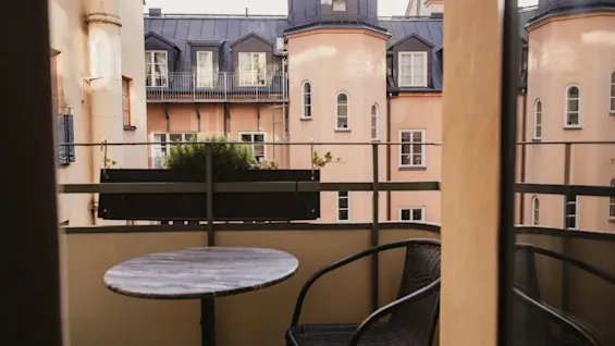 En hyggelig balkon på Home Hotel Wellington med bord og stol, med udsigt over charmerende bybygninger.