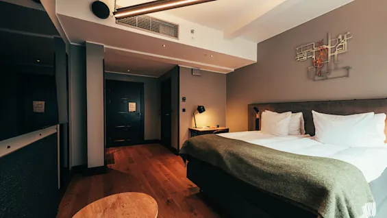 A modern hotel room with a comfortable bed, wooden floors, and stylish decor.