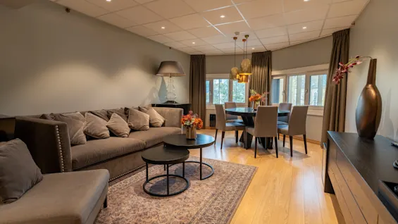 Et koselig og innbydende stue- og spiseområde med en stor sofa, salongbord og et spisebord dekket for et måltid.