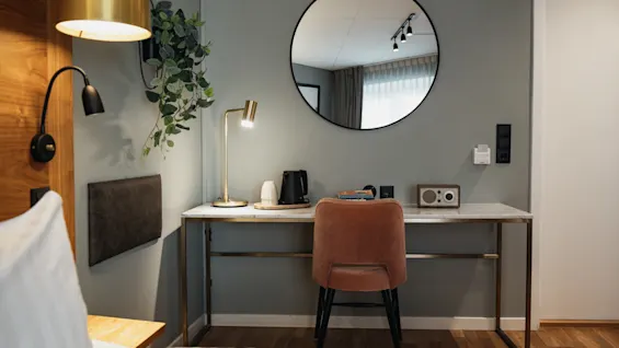 Et velindrettet hotelværelses skrivebord med en varm lampe, en elkedel til varme drikke og en radio, der skaber et behageligt rum.