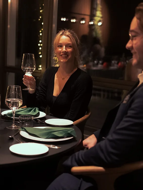 Ett par som njuter av en trevlig middag och skålar på en mysig restaurang.