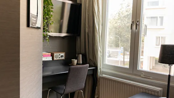En inbjudande arbetsplats i ett hotellrum, komplett med ett skrivbord, TV och ett fönster som ger naturligt ljus.
