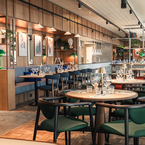 An inviting and modern restaurant interior with multiple tables set for dining, comfortable seating, and elegant decor.