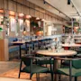Et innbydende og moderne restaurantinteriør med flere bord dekket for bespisning, komfortable sitteplasser og elegant innredning.