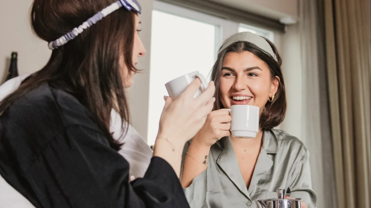 Two girls drinking coffee in the hotel bed at Clarion Hotel Sea U.