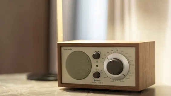 En radio med trekabinett og kremfarget front, som viser Bluetooth og Model One II, plassert på en marmoroverflate.