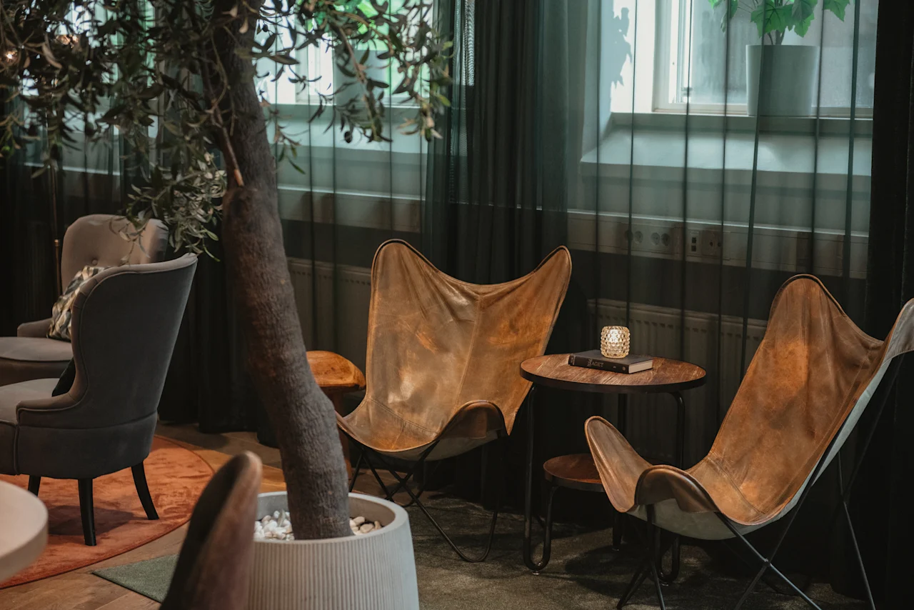 Cozy lounge area at Home Hotel Uppsala with comfortable seating, a small table, and a large potted plant.