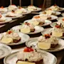 Open-faced sandwiches with creamy seafood salad and lemon wedges rest on ceramic plates, garnished with herbs, arranged in rows on a restaurant kitchen counter.