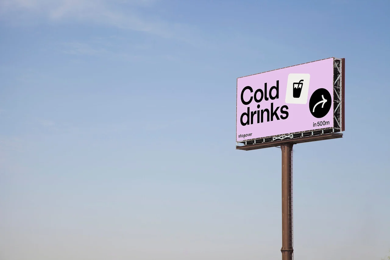 Mainostaulu, jossa lukee "Cold drinks", lasin kuvake ja nuoli, 500 metrin tauko, kirkasta taivasta vasten.