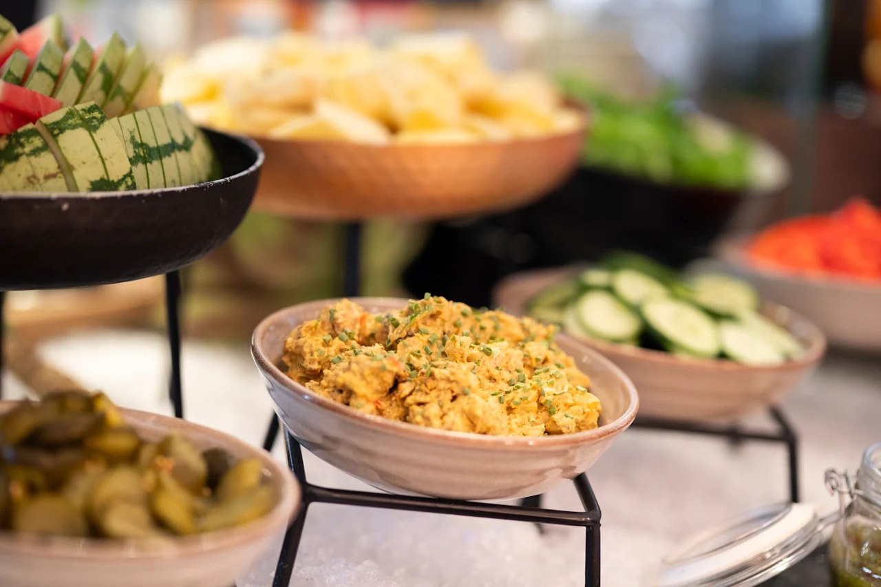 Eloisa noutopöytä, jossa on tuoretta vesimelonia, kermainen salaatti, viipaloituja kurkkuja ja muita herkullisia tarjottavia.