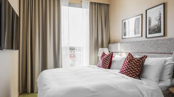 Et lyst og indbydende hotelværelse på Hernö Gin Hotel med en pænt redt seng, bløde puder og naturligt lys fra et stort vindue.