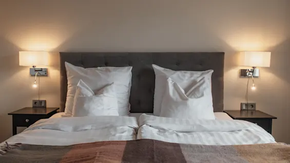 En indbydende hotelseng med bløde puder og varm belysning, perfekt til afslapning på Home Hotel Norre Park i Halmstad.