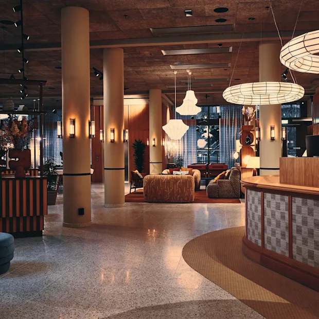 En moderne og innbydende hotellobby med en buet resepsjonsdisk, komfortable sitteplasser og unik takbelysning.