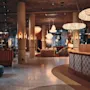 En moderne og innbydende hotellobby med en buet resepsjonsdisk, komfortable sitteplasser og unik takbelysning.