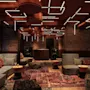 A cozy, modern lounge with brick walls, comfortable sofas, oriental rugs, and unique geometric ceiling lights.