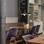 Et koselig kaféinteriør med trebord, lilla fløyelsstoler og et krittskilt som sier 'make yourself at home'.