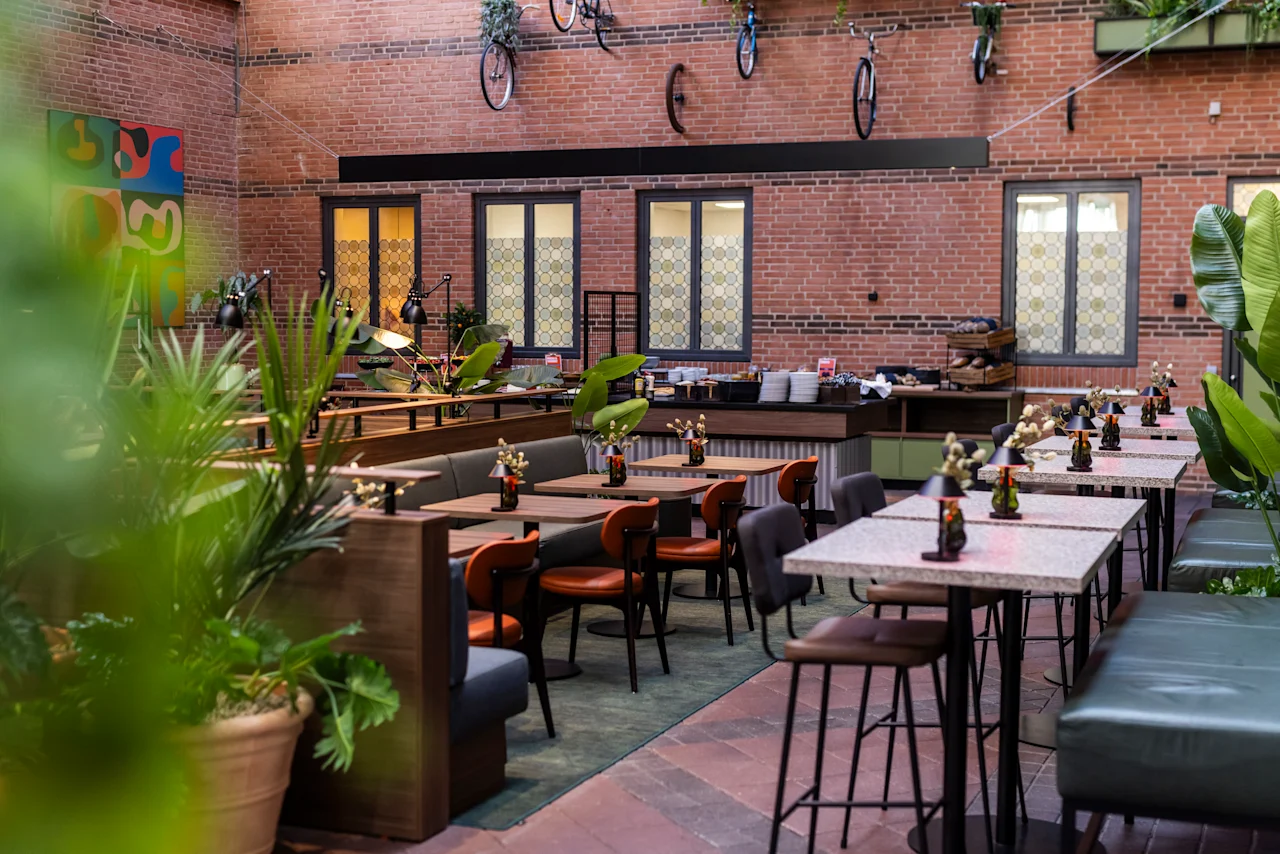 A stylish hotel restaurant at Comfort Hotel Vesterbro featuring brick walls, eclectic seating, green plants, and decorative bicycles.