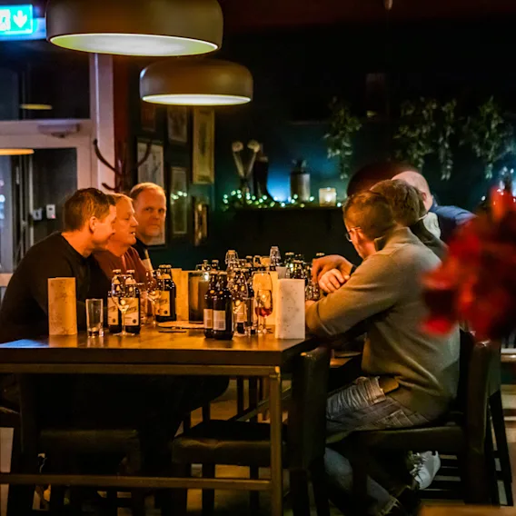 En grupp människor sitter runt ett högt bord i en mysig restaurang eller bar.
