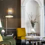 En hyggelig hotellounge med grønne og gule stole, lamper og et sofabord, der skaber en indbydende atmosfære.
