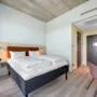 A modern and inviting hotel room with a comfortable bed, a small workspace, and warm lighting.