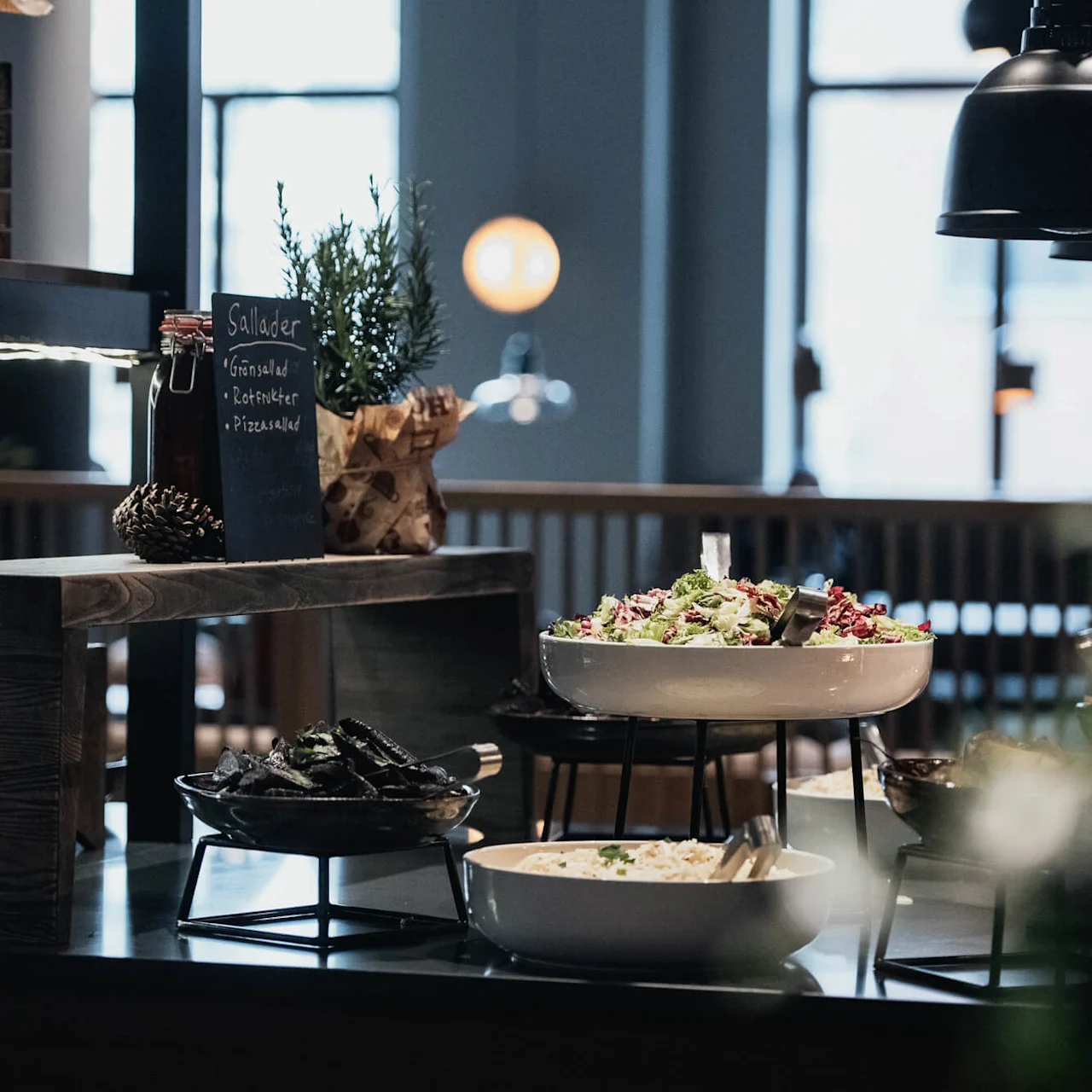 A buffet setup with salads and a blackboard displaying menu items in a cozy restaurant atmosphere.