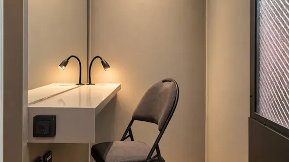 A small and modern workspace featuring a desk, a chair, and lighting.