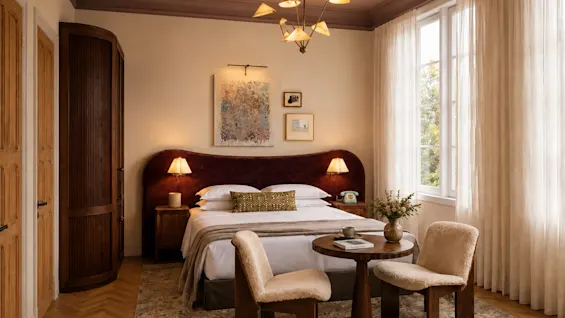 Ett varmt och inbjudande hotellrum med en bekväm säng, ett litet bord med två stolar och ett ljust fönster.