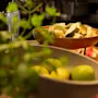 Et levende nærbilde av en fruktbuffé med skåler med fersk melon, vannmelon og andre frukter, innrammet av grønne planter.