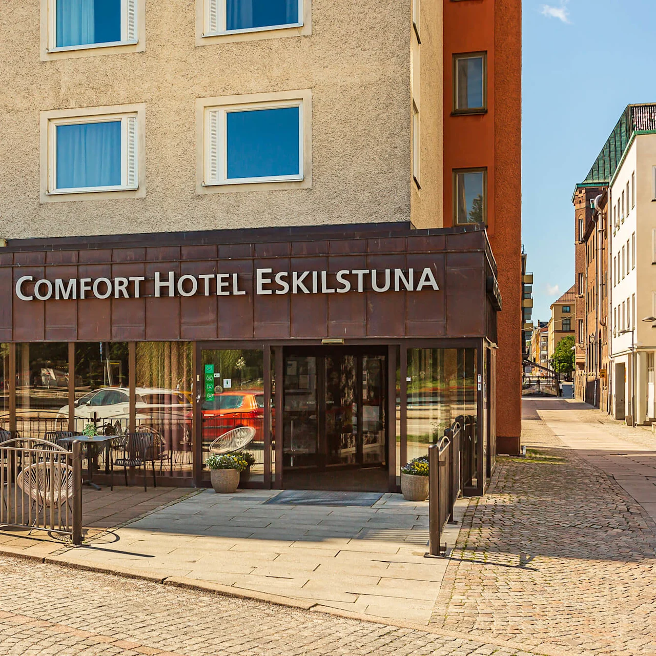 Comfort Hotel Eskilstuna -sisäänkäynti, jossa aitauksessa istuimia, kaupunkikadun ympäröimänä.