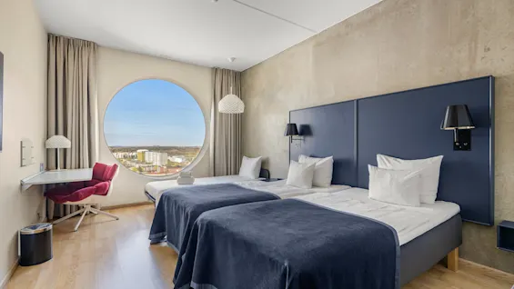 Ett ljust och modernt tvåbäddsrum på Quality Hotel Strawberry Arena, med ett unikt runt fönster och naturskön utsikt.