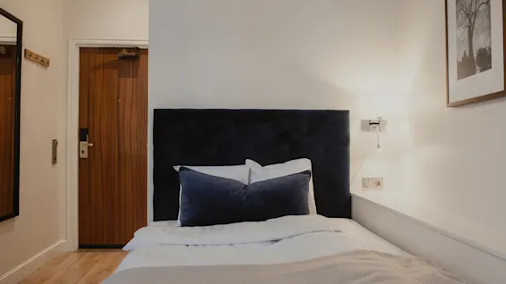 Et hyggeligt hotelværelse på Home Hotel Norre Park med en komfortabel seng, en trædør og et indrammet billede på væggen.