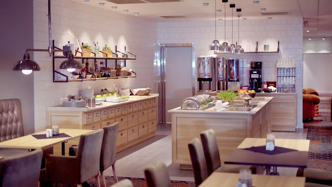 Modern hotel buffet with arranged dining tables, food stations and contemporary lighting in an inviting space.