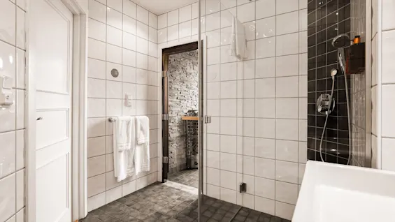 Moderni kylpyhuone Comfort Hotel Linkoping Cityssä, jossa on kaakeloitu suihkutila, valkoinen pesuallas ja näkymä saunaan.