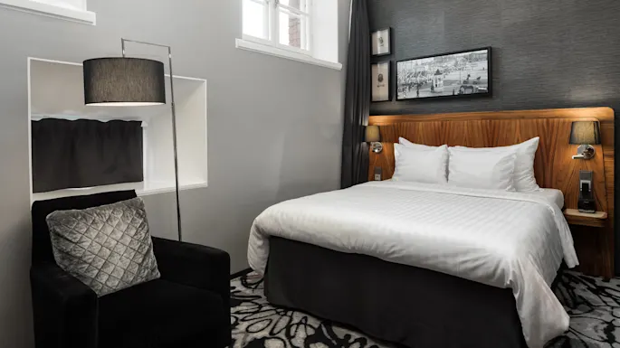 Et soverom med pent oppredd seng, stemningsbelysning, og moderne dekor i et innendørs miljø.