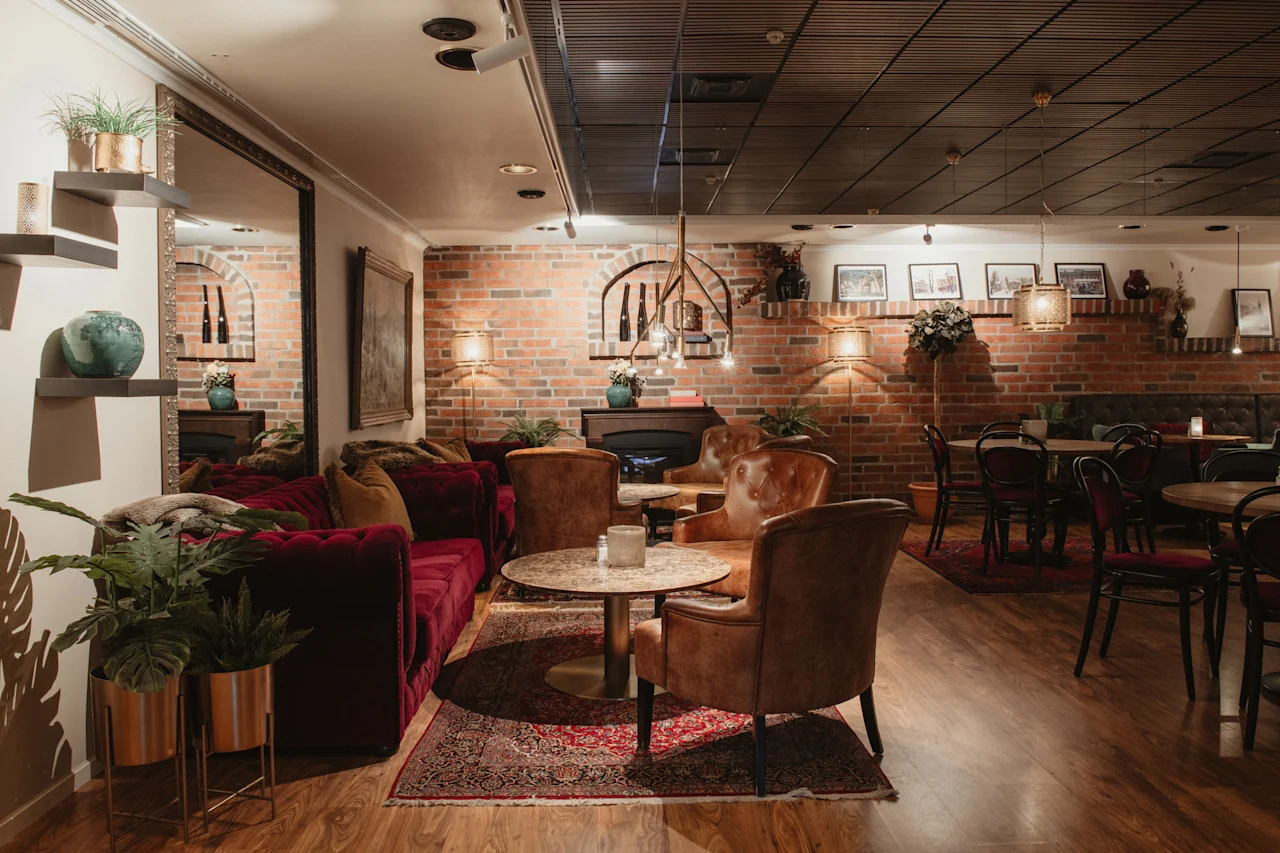 Ett varmt och inbjudande loungeområde med tegelväggar, plyschmöbler och mjuk belysning, perfekt för avkoppling eller avslappnad middag.