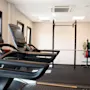 Et moderne treningsstudio med to tredemøller i forgrunnen og et knebøystativ med fargerike vektplater i bakgrunnen.