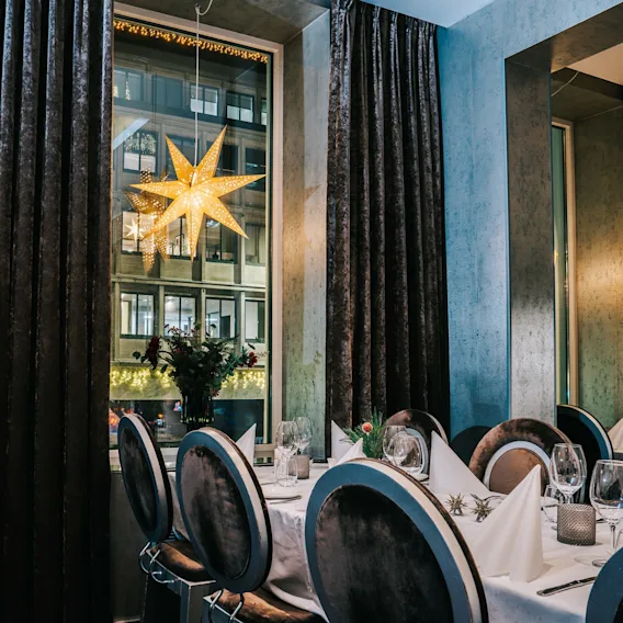 An elegantly set dining table in a restaurant decorated for Christmas with a glowing star in the window.