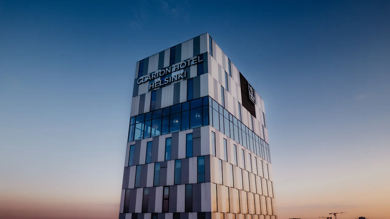 Moderni hotellirakennus, Clarion Hotel Helsinki, kirkasta sinistä taivasta vasten auringonlaskun värien kera.