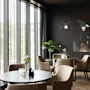 Et elegant og innbydende salongområde med komfortable sitteplasser, runde bord og store vinduer mot grøntområder.