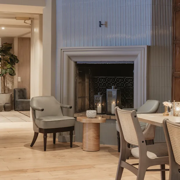 En varm och inbjudande hotellounge med öppen spis, bekväma sittplatser och mjuk belysning från levande ljus.